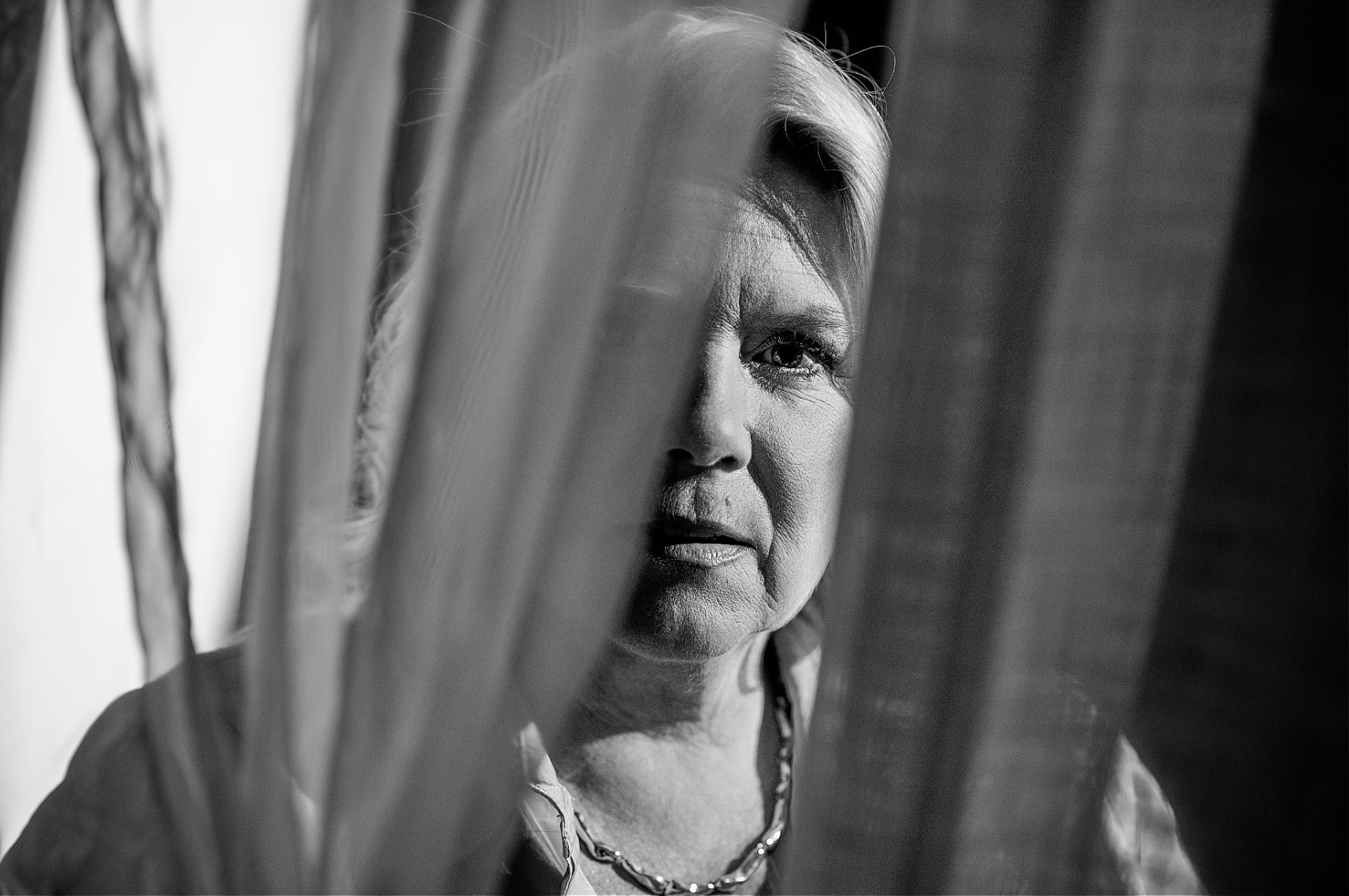 Black and white portrait of Camilla behind a sheer curtain